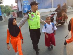 Semangat Pagi, Anggota Polsek Kragan Bantu Sebrangkan Anak-anak Sekolah